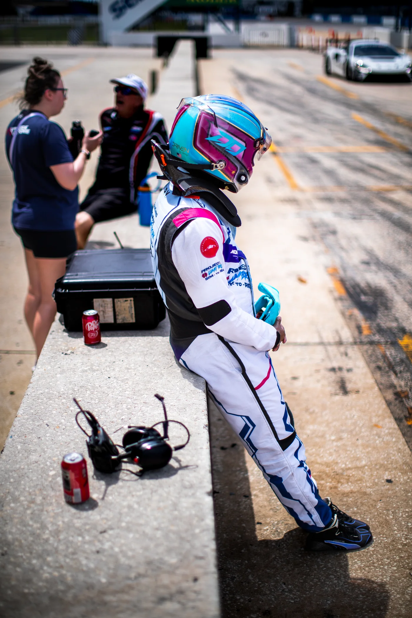 Daniel Oliver, helmet on, leaning on the pit wall between sessions at Sebring