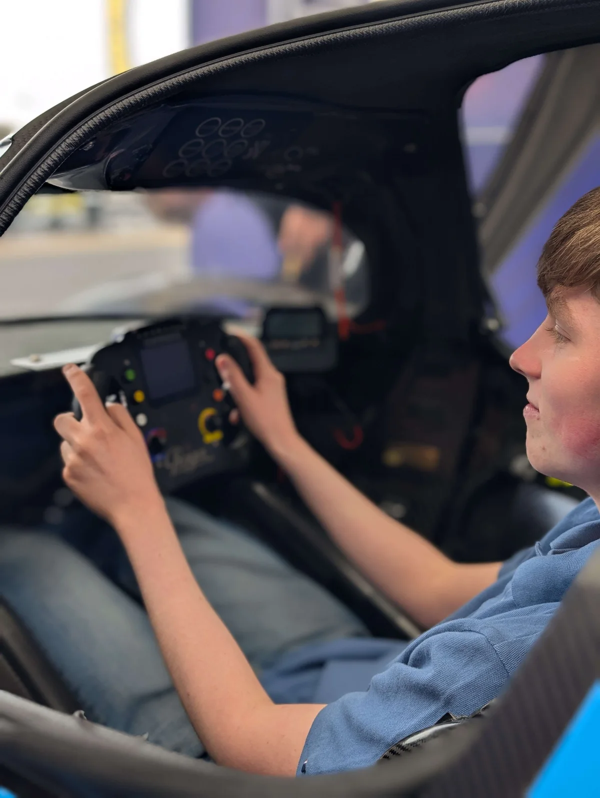 A young fan from the paddock sitting in the prototype, hands on the steering wheel